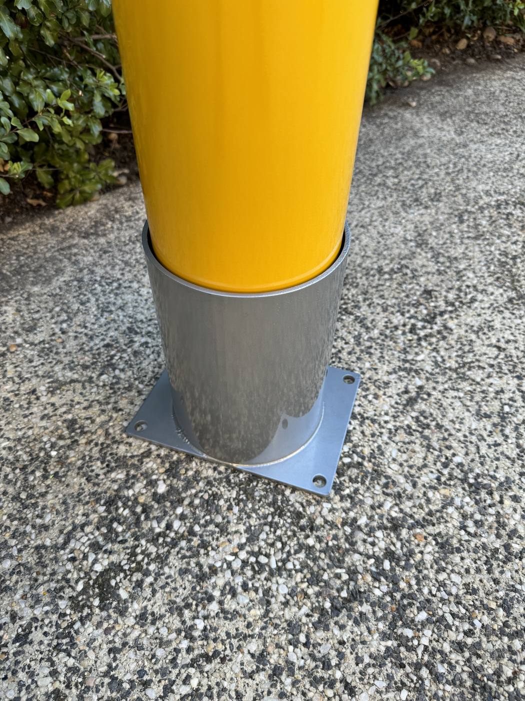 Removable bollard installed into an in-ground sleeve on a concrete driveway